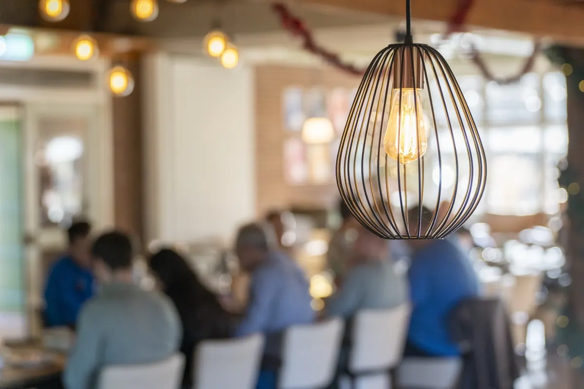 Ruime zaal met gedekte tafels en mensen in gesprek